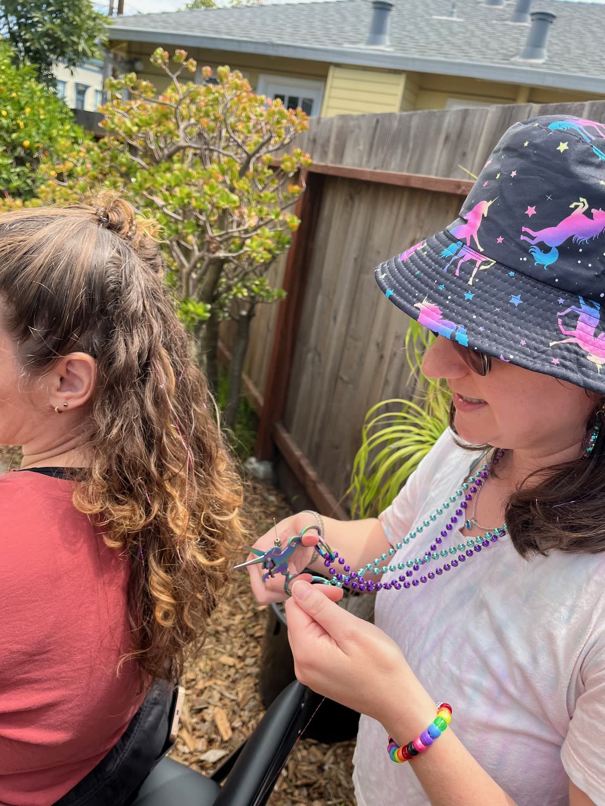 Hands tying a single sparkle strand into curly hair